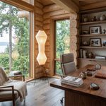 Cosima Hourglass Washi Paper Floor Lamp | Japanese Wabi-Sabi Paper and Black Tripod | Illuminating a rustic log cabin home office workspace with a wooden executive desk | Severn Lighting