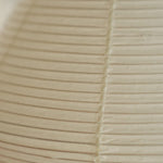 Cosima Hourglass Washi Paper Floor Lamp | Japanese Wabi-Sabi Paper and Black Tripod | Extreme macro texture close-up showcasing the ribbed weave of the unlit cream Washi paper shade | Severn Lighting