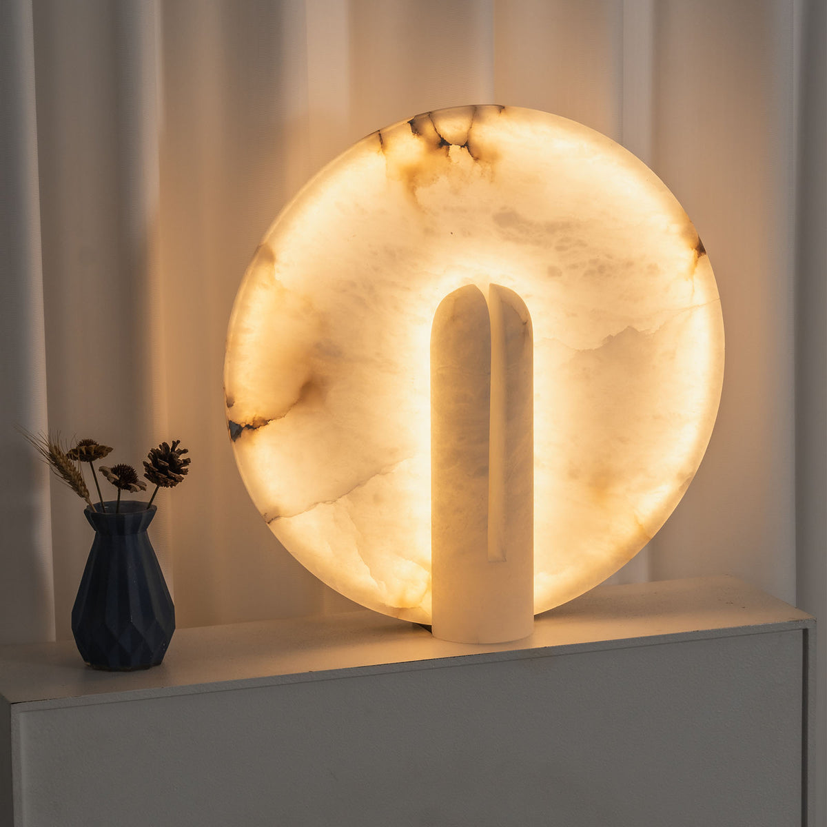Elvire Alabaster Disc Table Lamp | Natural Alabaster | Close-up view displayed on a window ledge beside a decorative vase | Severn Lighting