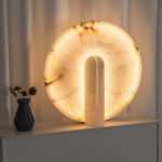 Elvire Alabaster Disc Table Lamp | Natural Alabaster | Close-up view displayed on a window ledge beside a decorative vase | Severn Lighting