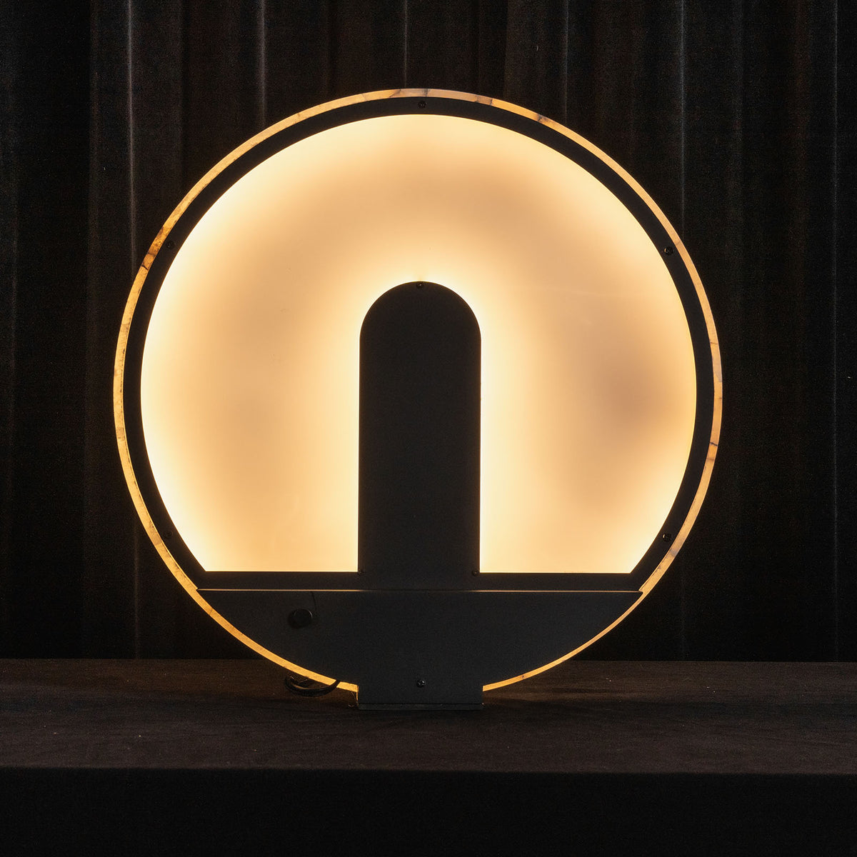 Elvire Alabaster Disc Table Lamp | Natural Alabaster | Backlit silhouette view highlighting the glowing circular disc design | Severn Lighting