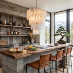 Ethereal Icicle Waterfall Chandelier | Frosted Icicle Glass and Gold Brass | Suspended above a rustic home bar counter with leather stools looking out at snowy peaks | Severn Lighting