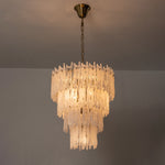 Ethereal Icicle Waterfall Chandelier | Frosted Icicle Glass and Gold Brass | Symmetrical view of the multi-layered fixture fully lit and glowing against a plain dark wall | Severn Lighting