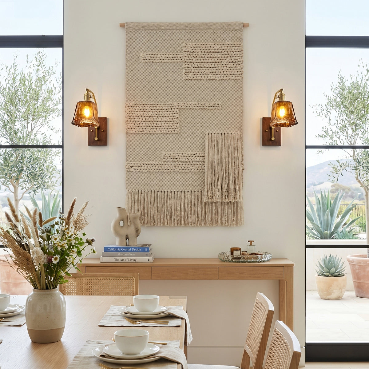 Everett Amber Ripple Wall Sconce | Amber Rippled Glass and Walnut Wood | Flanking a fabric wall tapestry above a dining table setup in a bright dining area | Severn Lighting
