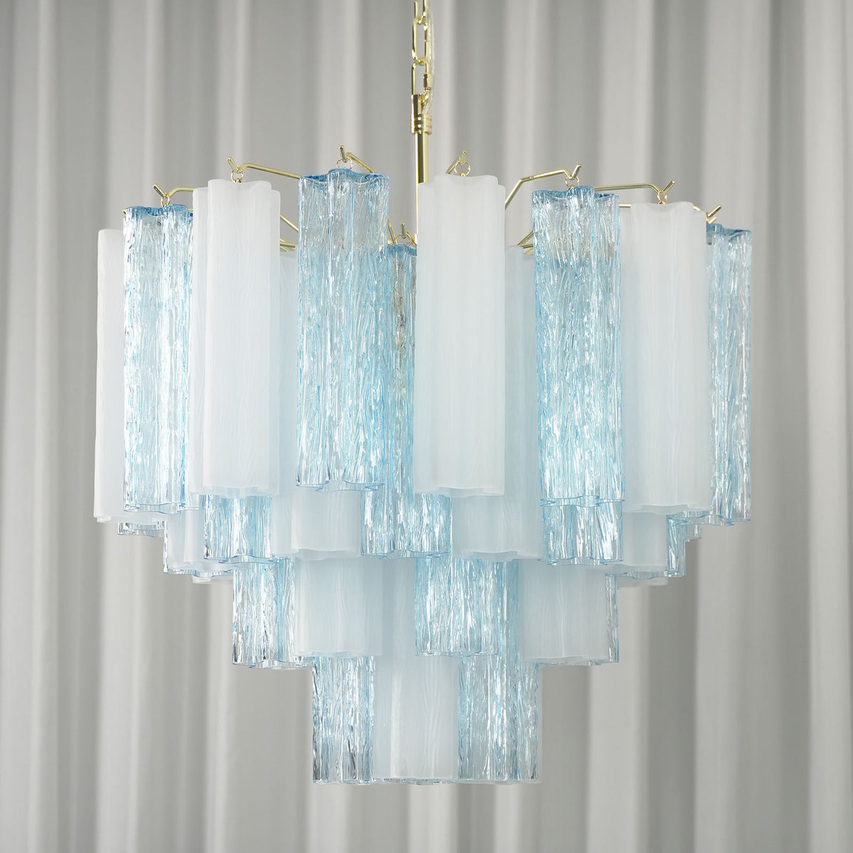 Givrane Two-Tone Glass Tube Tiered Chandelier | Two-Tone Glass and Brass | Studio product view hanging gracefully against a striped white backdrop | Severn Lighting