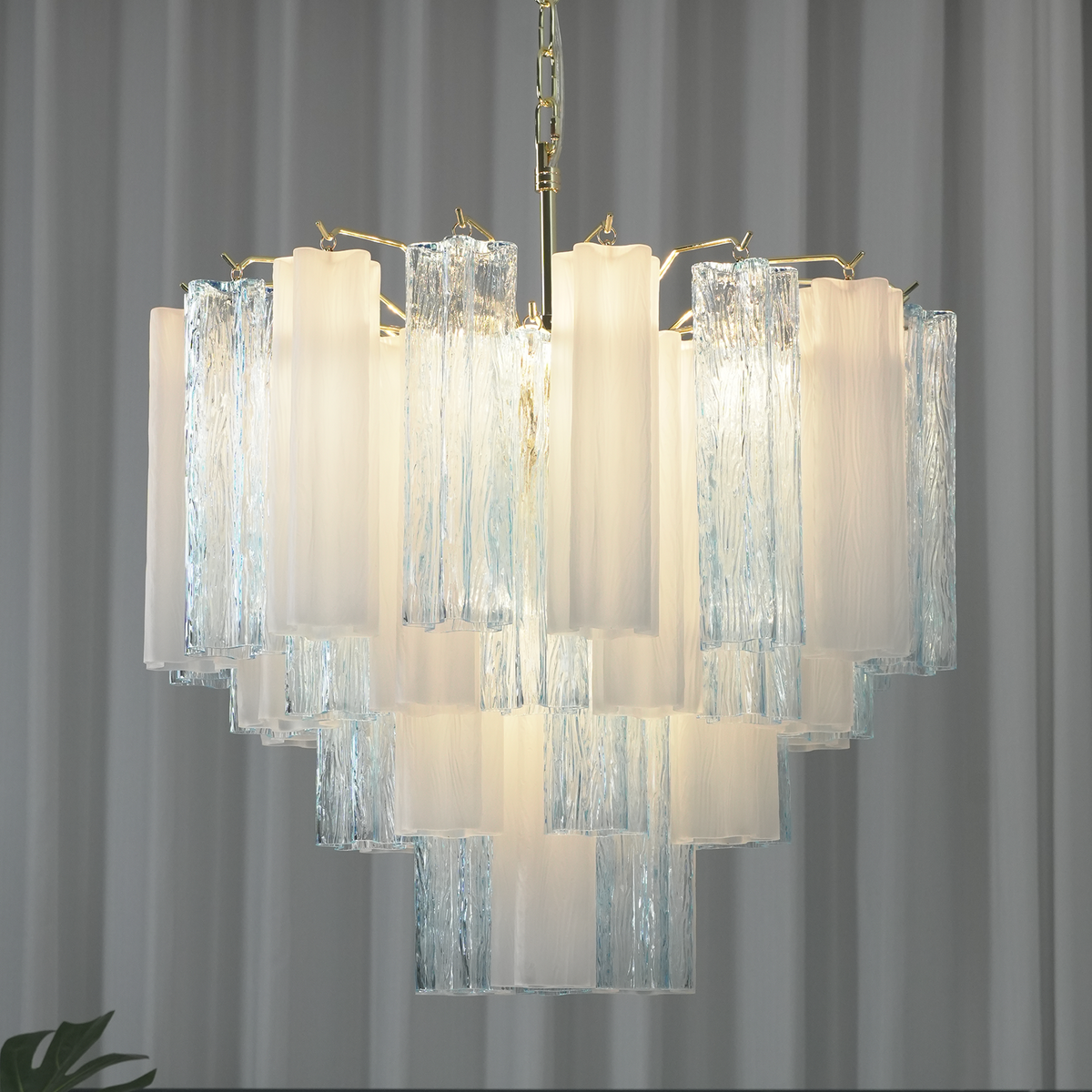 Givrane Two-Tone Glass Tube Tiered Chandelier | Two-Tone Glass and Brass | Full product view glowing brightly illuminated on a dark grey background | Severn Lighting