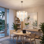 Givrane Two-Tone Glass Tube Tiered Chandelier | Two-Tone Glass and Brass | Displayed over a round study table in a casual room with balcony doors | Severn Lighting