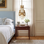 Isambard Crowned Crystal Basket Pendant Light | Cut Crystal and Brass | Hanging beside a blue upholstered bed over a wooden nightstand | Severn Lighting