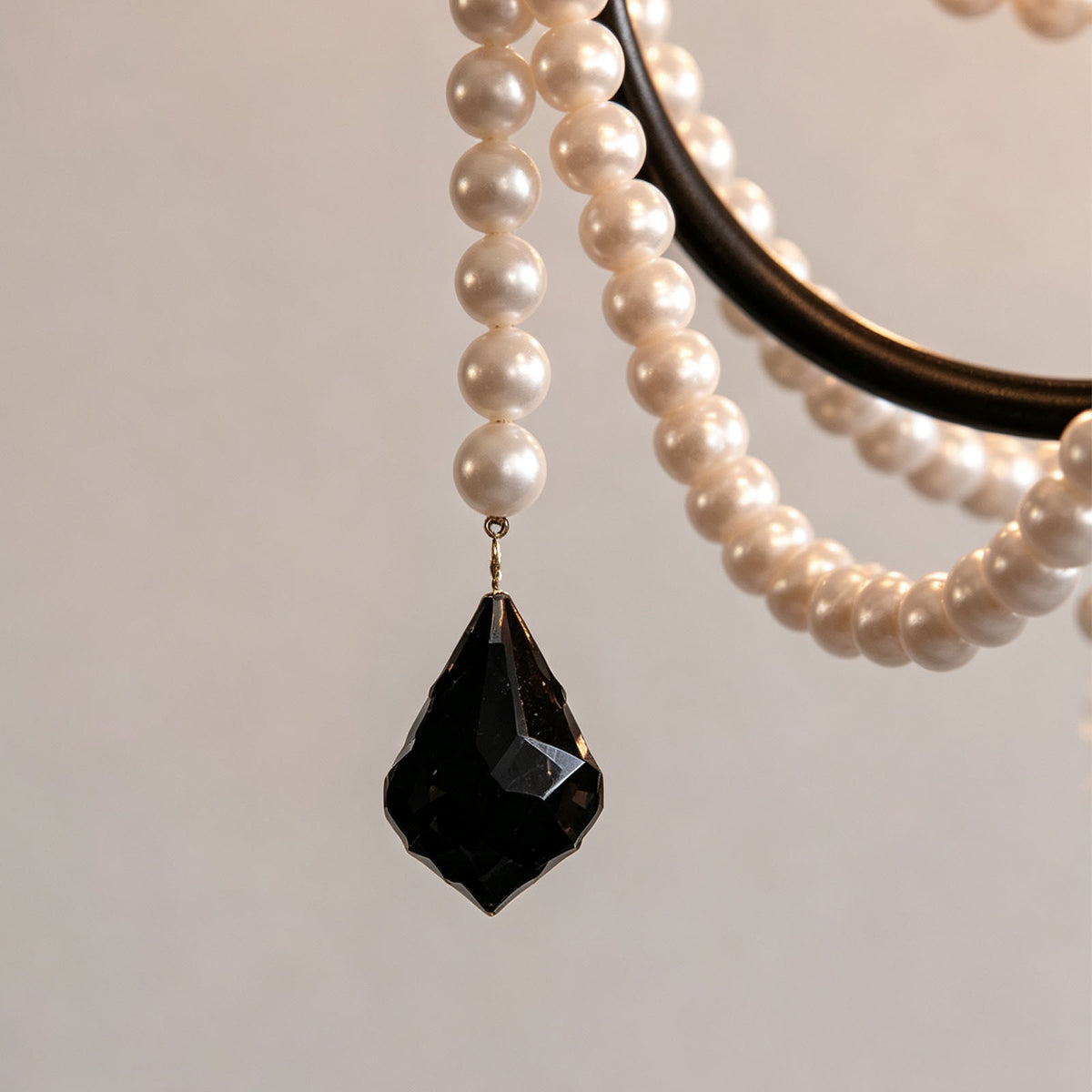 Isolde Pearl Swag Candle Chandelier | Pearl Beads, Crystal and Metal | Macro shot of a black faceted teardrop crystal pendant and pearl strand | Severn Lighting