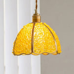 Liora Mosaic Glass Pendant Light | Yellow Mosaic Glass and Brass | Single yellow mosaic glass pendant fully lit and casting warm glow on a plain grey wall | Severn Lighting