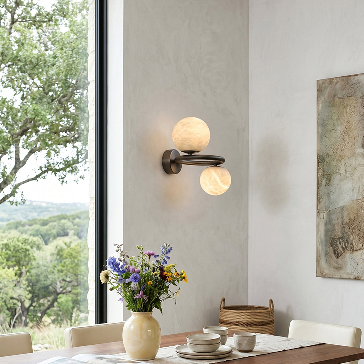Lucern Twin Globe Alabaster Wall Sconce | Natural Alabaster and Matte Black Metal | Styled on a dining room wall near a window overlooking scenic green hills | Severn Lighting