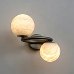 Lucern Twin Globe Alabaster Wall Sconce | Natural Alabaster and Matte Black Metal | Angled studio display against a clean grey background with both spheres fully illuminated | Severn Lighting