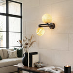 Lucern Twin Globe Alabaster Wall Sconce | Natural Alabaster and Matte Black Metal | Illuminating a living room corner above a wooden table with books and a candle | Severn Lighting