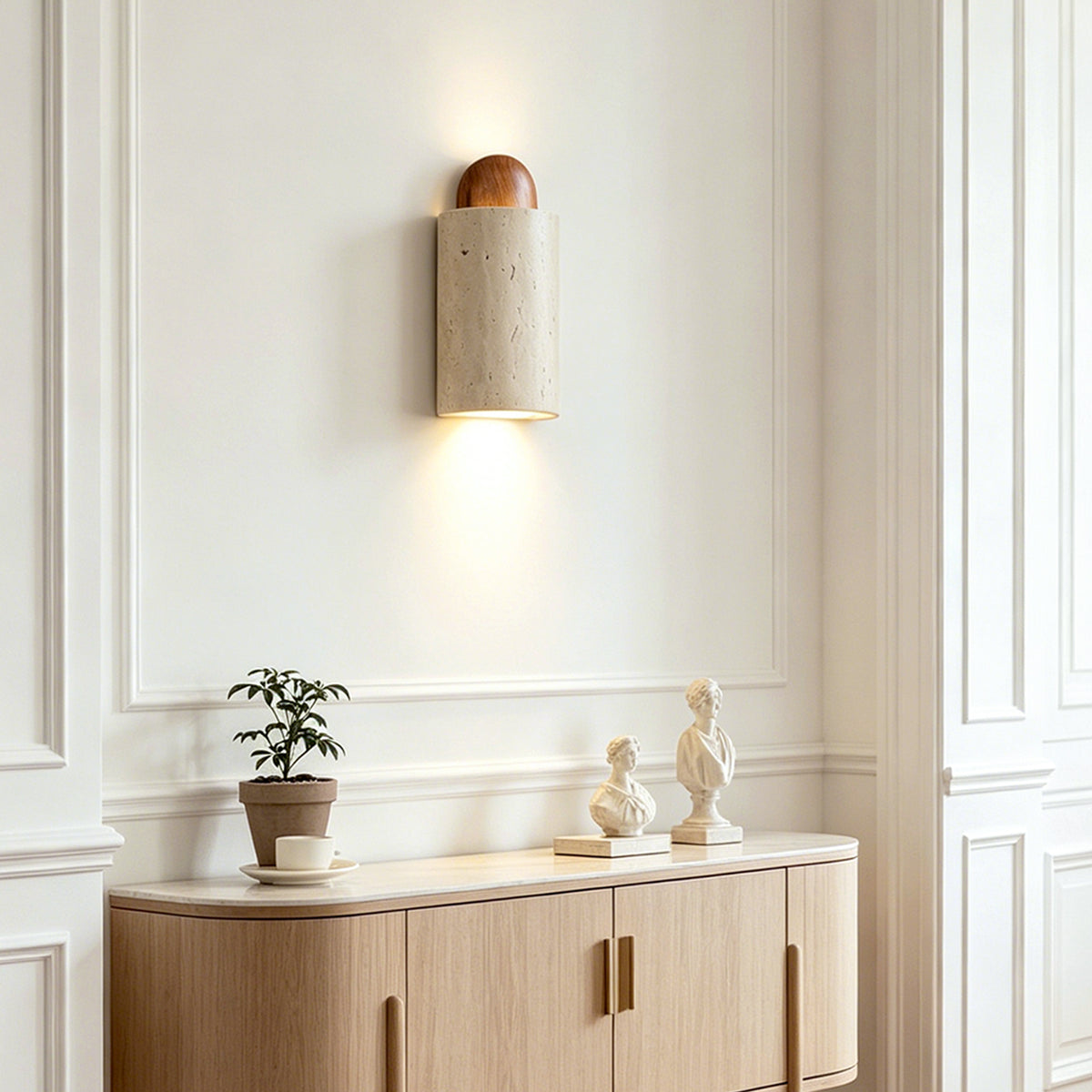 Lyra Travertine Shield Wall Lamp | Travertine, Wood, Metal | Positioned on a minimalist white wall as modern accent lighting above an elegant wooden sideboard cabinet | Severn Lighting