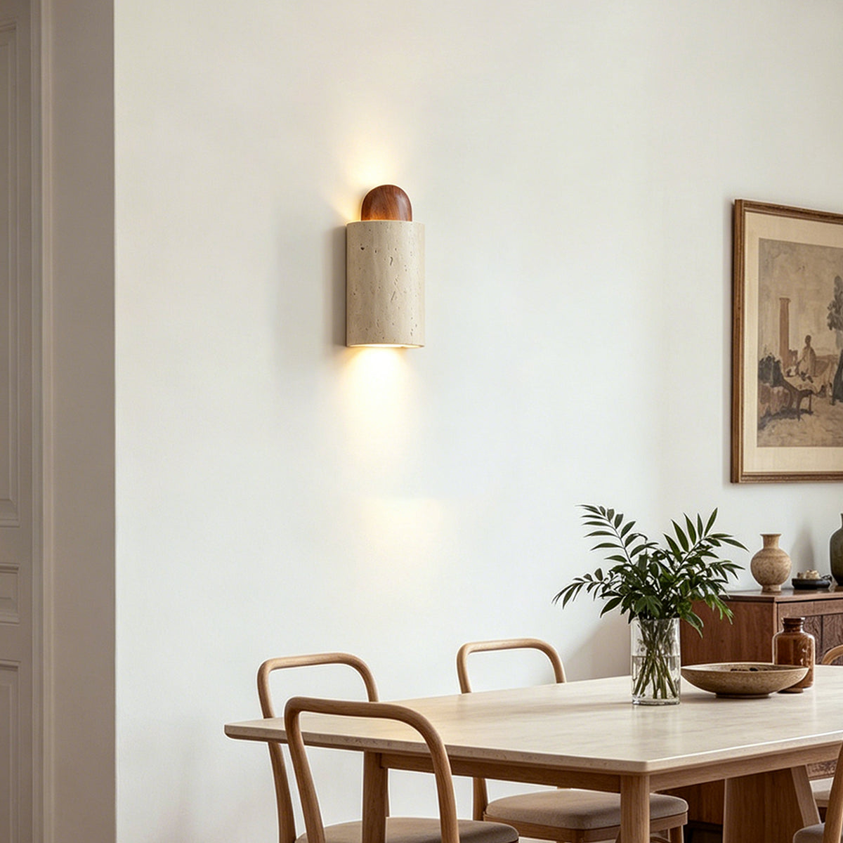 Lyra Travertine Shield Wall Lamp | Travertine, Wood, Metal | Hanging on a neutral wall to provide cozy ambient light over a light wood dining table with chairs | Severn Lighting
