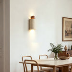 Lyra Travertine Shield Wall Lamp | Travertine, Wood, Metal | Hanging on a neutral wall to provide cozy ambient light over a light wood dining table with chairs | Severn Lighting