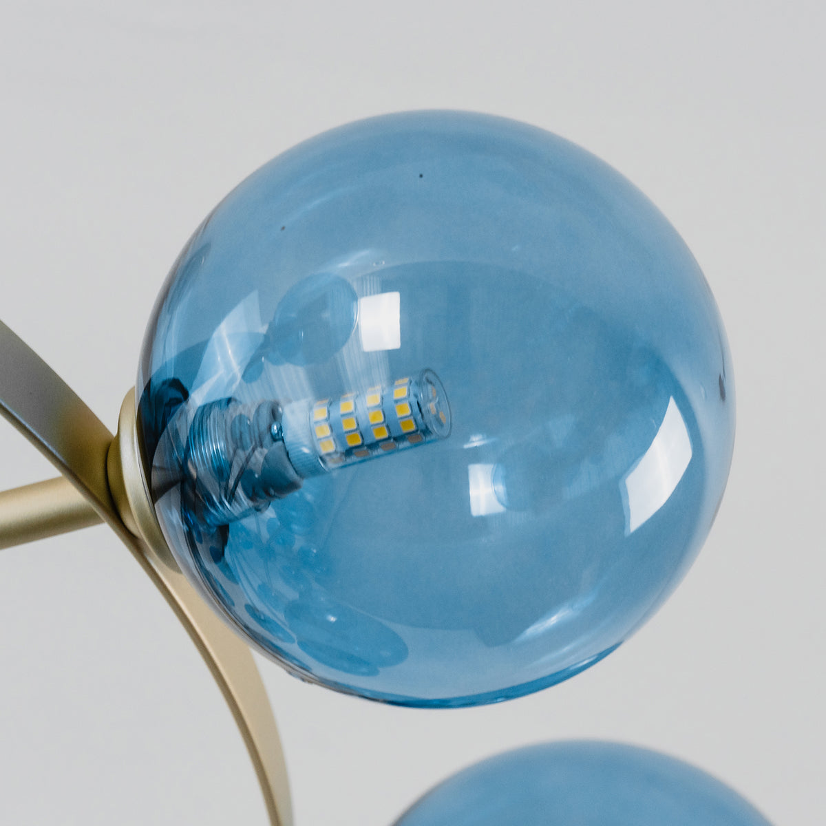 Marisol Aquamarine Glass Bubble Chandelier | Aquamarine Glass and Brass | Macro view of a single aquamarine glass bubble attached to a brass arm | Severn Lighting