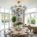 Marisol Aquamarine Glass Bubble Chandelier | Aquamarine Glass and Brass | Hanging above a round dining table in a bright coastal dining room | Severn Lighting