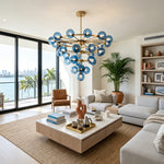 Marisol Aquamarine Glass Bubble Chandelier | Aquamarine Glass and Brass | Installed in a coastal home living space featuring large open balcony doors | Severn Lighting