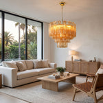 Merlande Amber Glass Tube Tiered Chandelier | Fluted Amber Glass and Brass | Displayed in a luxury living room with beige sofas and garden patio windows | Severn Lighting