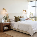 Merrick Fluted Glass Bell Wall Lamp | Fluted Glass and Brass | Displayed on a bedroom wall above a nightstand beside a bed | Severn Lighting