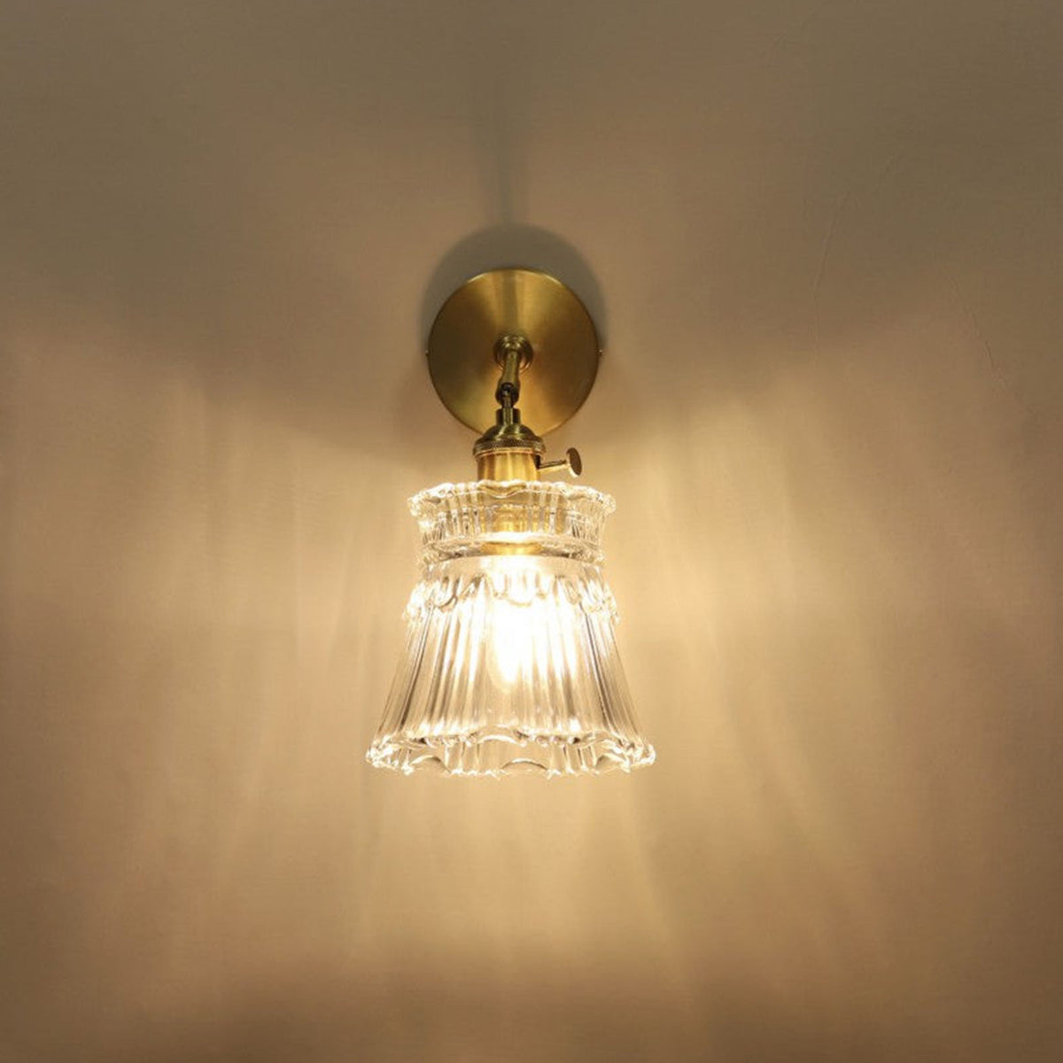 Merrick Fluted Glass Bell Wall Lamp | Fluted Glass and Brass | Front illuminated view showing warm light reflection on a dark backdrop | Severn Lighting