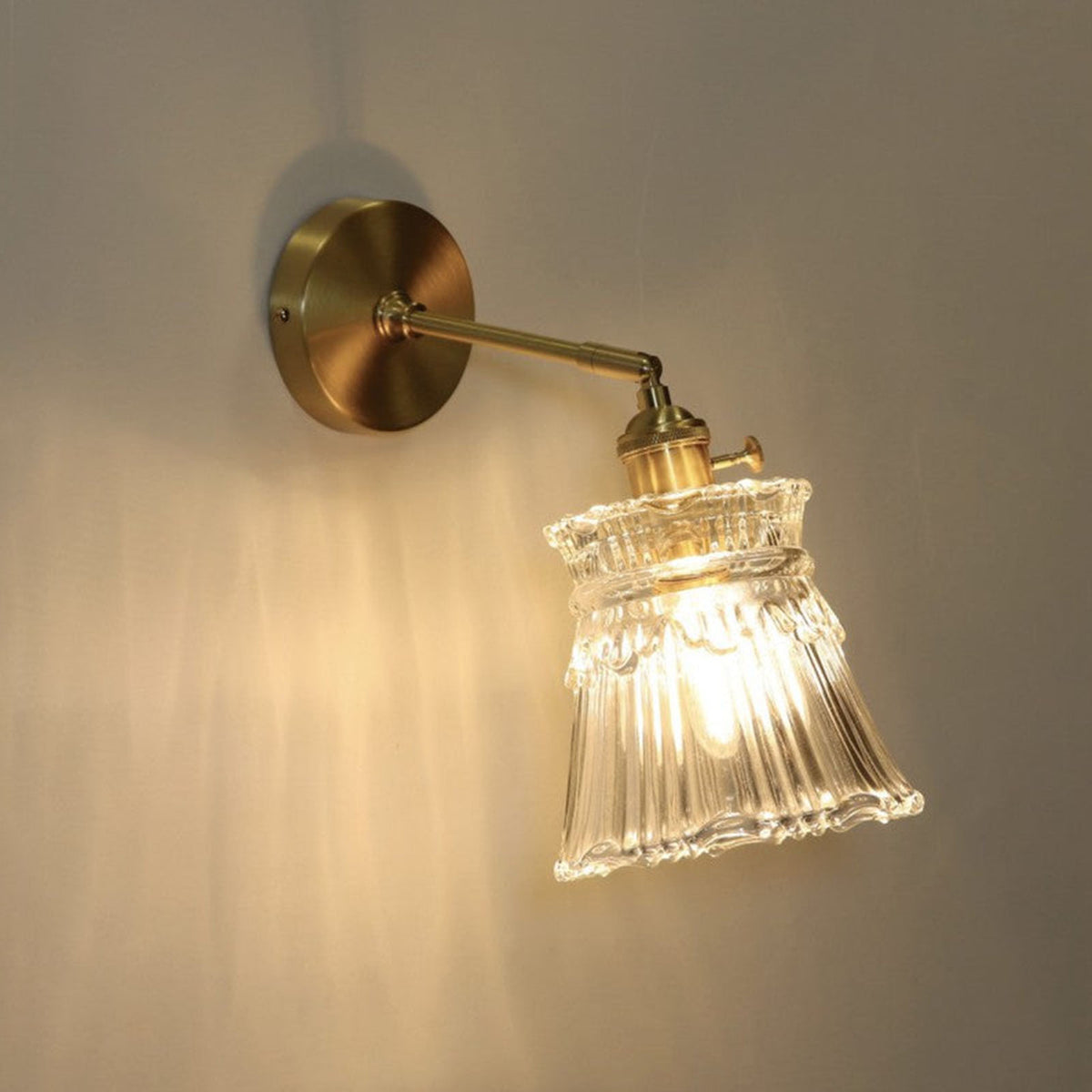 Merrick Fluted Glass Bell Wall Lamp | Fluted Glass and Brass | Angled illuminated view displayed against a dark studio background | Severn Lighting