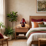 Mouchelle Mushroom Lamp | Red Glass and Brass | Lit beside a wooden bed frame in a warm earth-tone room | Severn Lighting