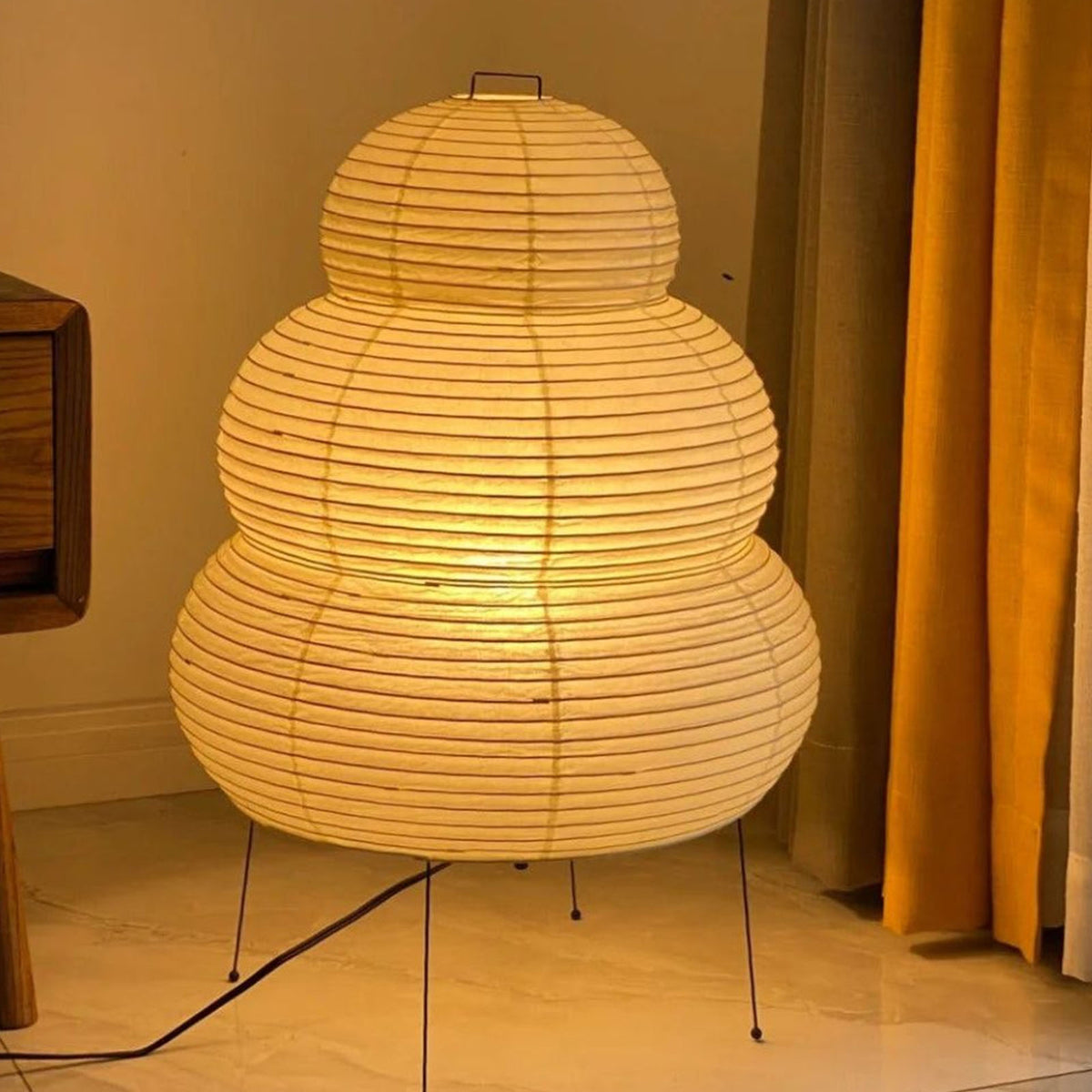 Nerine Tiered Washi Paper Table Lamp | Washi Paper and Metal | Full glowing view standing on the floor next to curtains | Severn Lighting