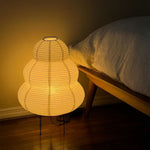 Nerine Tiered Washi Paper Table Lamp | Washi Paper and Metal | Glowing softly on the floor next to a bed in a dark room | Severn Lighting