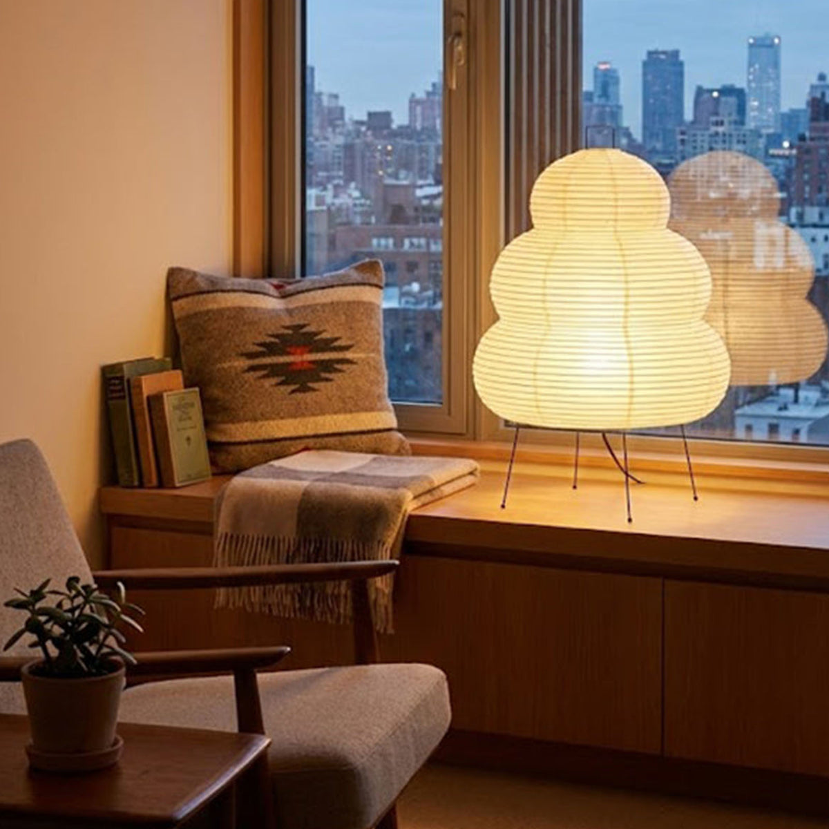 Nerine Tiered Washi Paper Table Lamp | Washi Paper and Metal | Set on a cozy window seat overlooking a city skyline | Severn Lighting