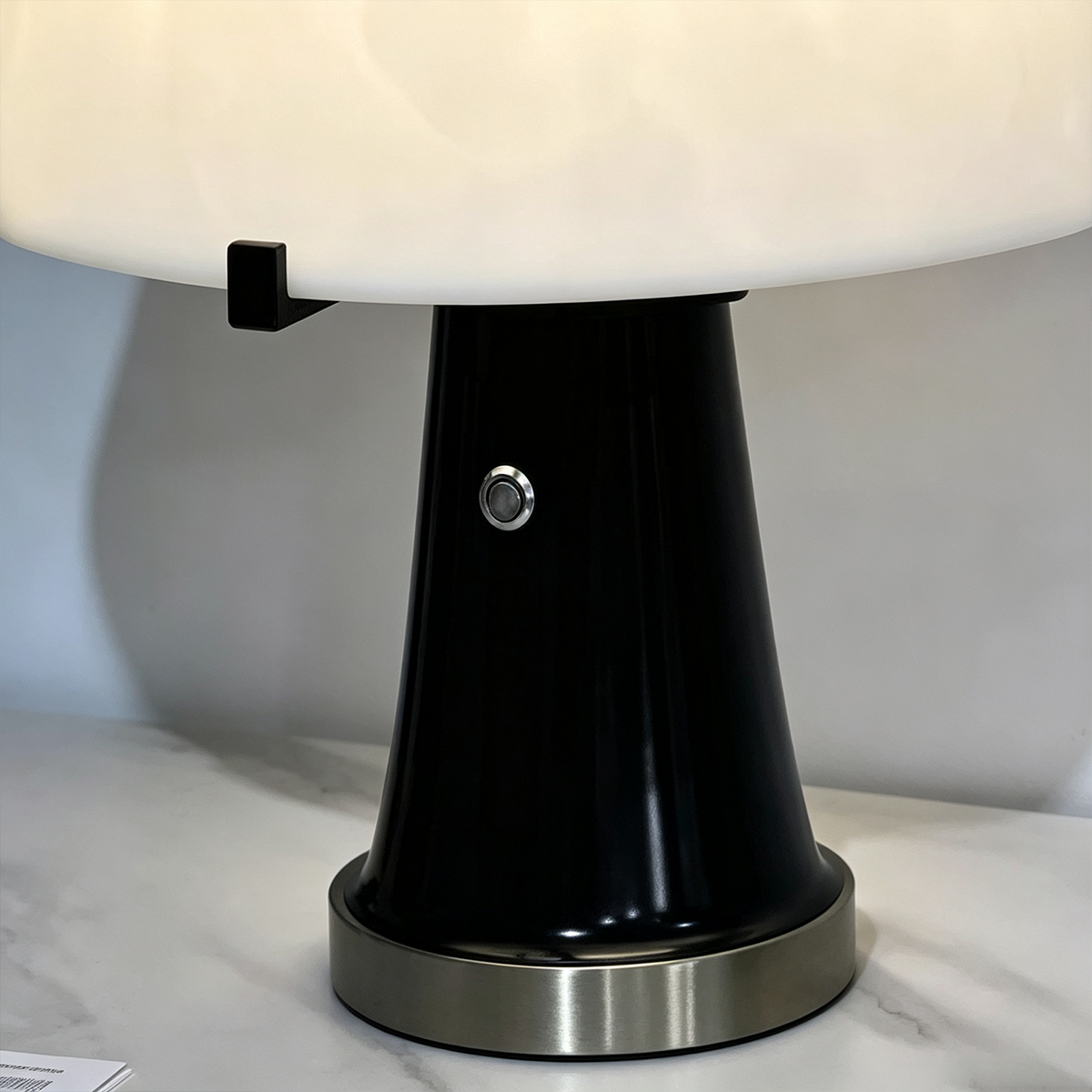 Orsino Alabaster Trapezoid Table Lamp | Natural Alabaster, Black Metal and Brass | Close-up view of the black lamp body featuring a small metal switch | Severn Lighting