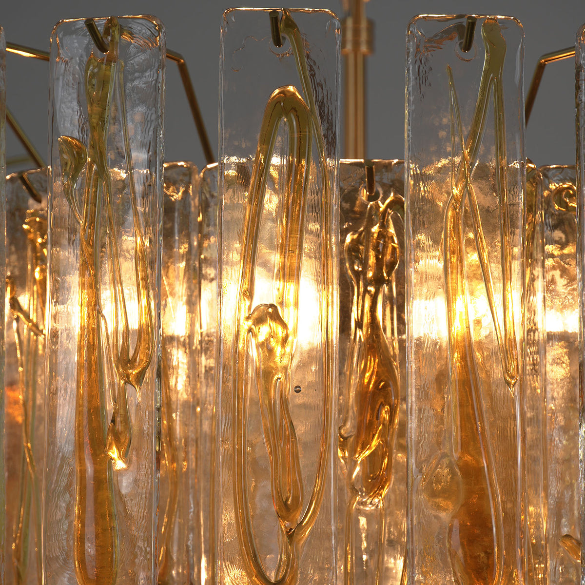 Orvelane Amber Swirl Glass Tiered Chandelier | Amber Swirl Glass and Brass | Macro detail shot highlighting warm light glowing through amber swirl glass | Severn Lighting