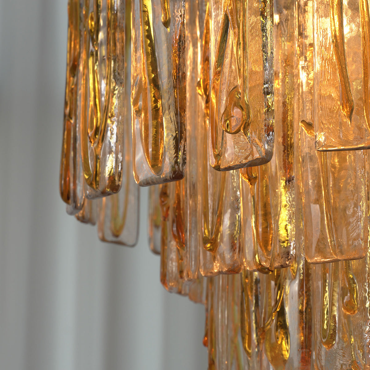 Orvelane Amber Swirl Glass Tiered Chandelier | Amber Swirl Glass and Brass | Close-up side view of cascading amber swirl glass panels on brass frame tiers | Severn Lighting