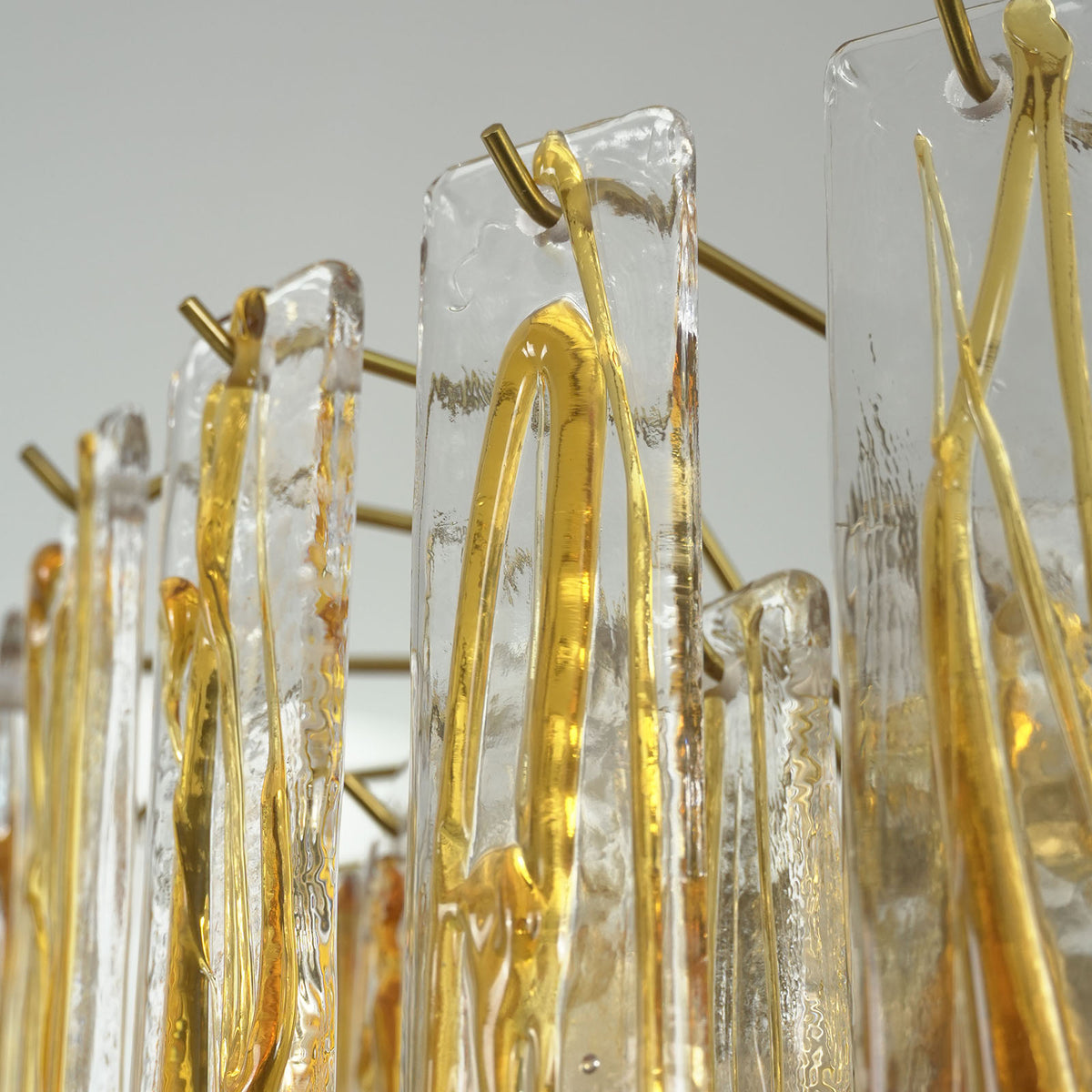 Orvelane Amber Swirl Glass Tiered Chandelier | Amber Swirl Glass and Brass | Angled detail view showing translucent amber swirl glass panels on brass hooks | Severn Lighting