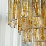 Orvelane Amber Swirl Glass Tiered Chandelier | Amber Swirl Glass and Brass | Side close-up view of illuminated tiered amber swirl glass panels | Severn Lighting