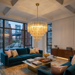Orvelane Amber Swirl Glass Tiered Chandelier | Amber Swirl Glass and Brass | Suspended in a luxury high-ceiling living room with blue sofas and city view windows | Severn Lighting