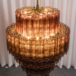 Ottoline Tiered Glass Chandelier | Textured Glass and Brass | Warm glowing full view of the lit chandelier in a studio | Severn Lighting