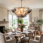 Perrin Smoked Glass Cloud Chandelier | Smoked Glass and Brass | Illuminating a cozy dining area with a stone fireplace | Severn Lighting