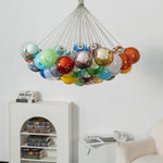 Rainbow Glass Bubble Cluster Chandelier | Multi-colored Blown Glass and Metal Cords | Suspended in a minimalist white interior space above a white storage cabinet with decorative items | Severn Lighting