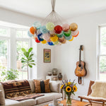 Rainbow Glass Bubble Cluster Chandelier | Multi-colored Blown Glass and Metal Cords | Adding a cheerful touch to a cozy living room with a brown leather couch and an acoustic guitar on the wall | Severn Lighting