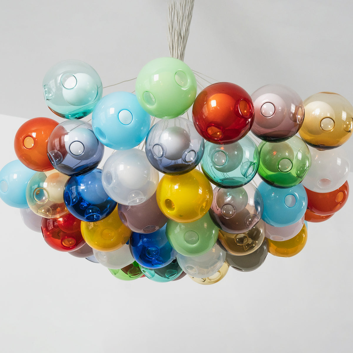 Rainbow Glass Bubble Cluster Chandelier | Multi-colored Blown Glass and Metal Cords | Product display showing the unlit colorful cluster hanging against a plain light grey studio background | Severn Lighting
