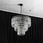 Rainer Cascading Glass Rod Chandelier | Clear Glass and Black Metal | Studio full shot of the chandelier illuminated against dark curtains | Severn Lighting