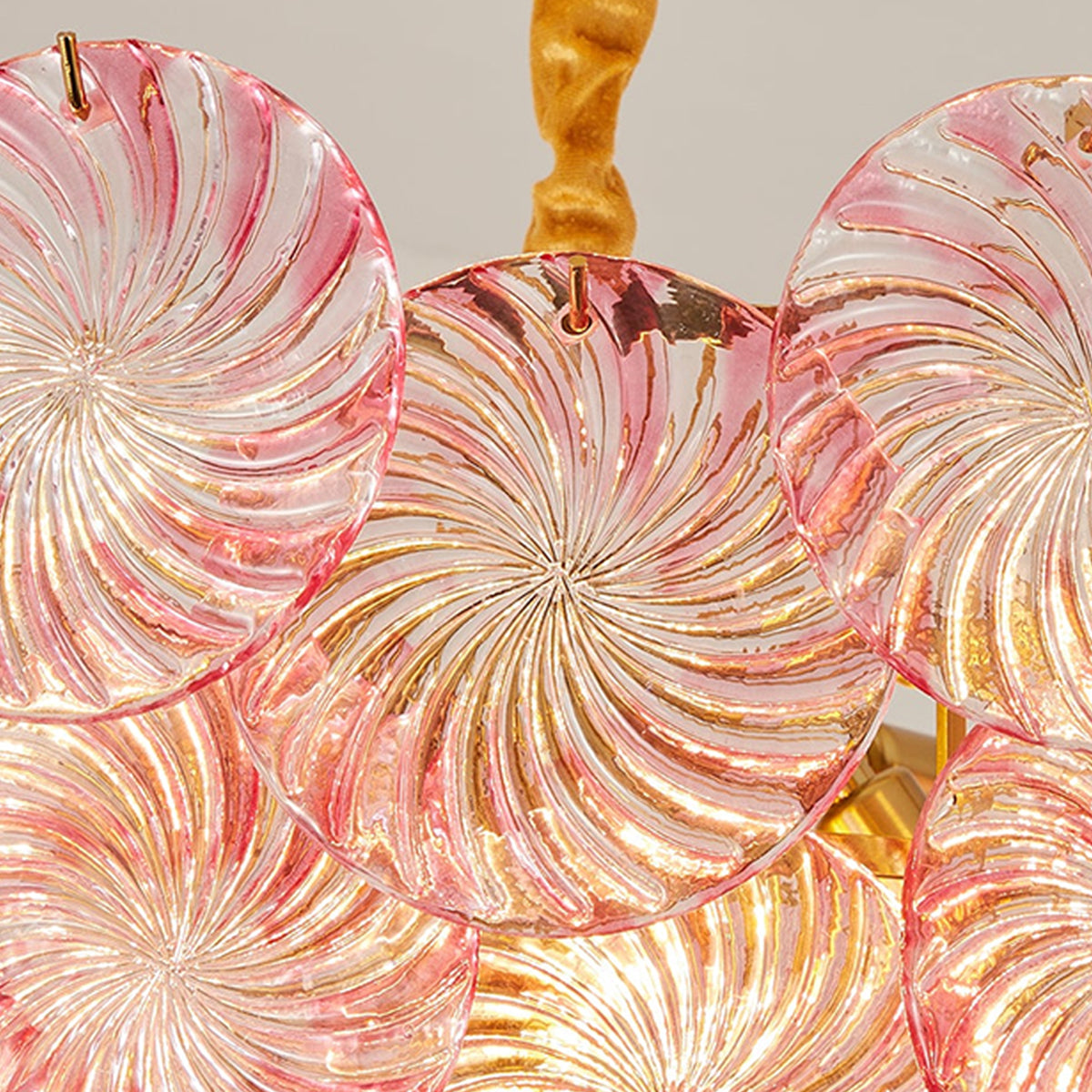 Rosalind Petal Glass Chandelier | Textured Spiral Pink Glass and Gold Metal | Macro view of the lit pink fixture highlighting the internal gold frame and glowing bulbs | Severn Lighting