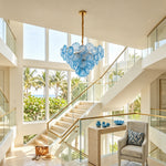 Rosalind Petal Glass Chandelier | Textured Spiral Blue Glass and Gold Metal | Suspended in a bright open staircase hallway with glass railings and sunny window views | Severn Lighting