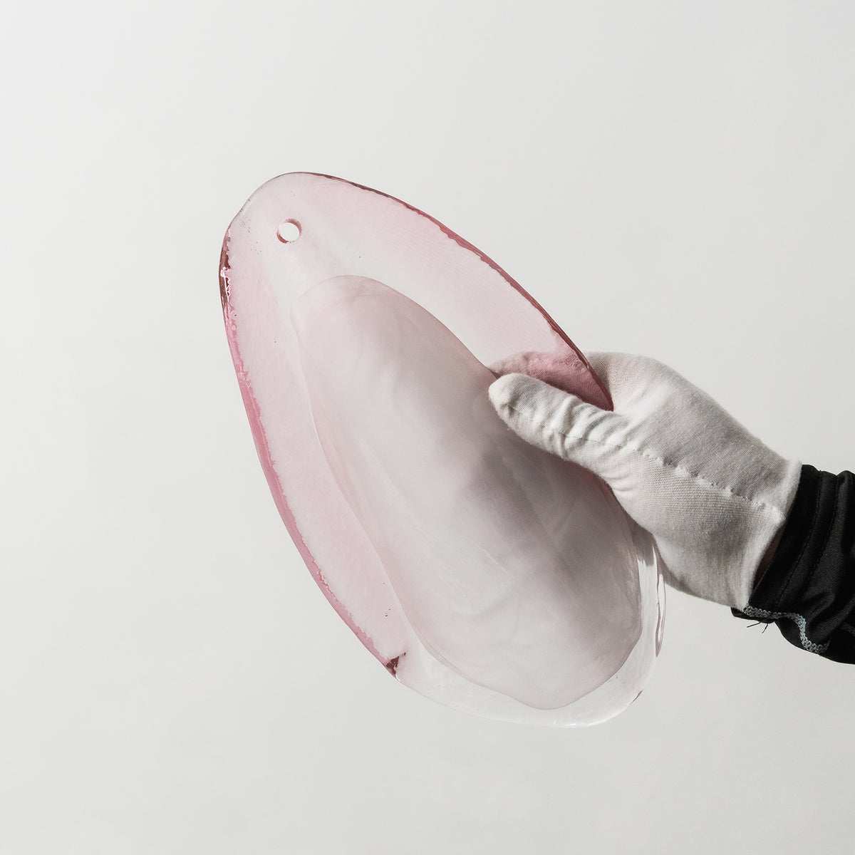 Rosalind Rose Glass Wall Sconce | Glass, Metal | Detail shot showing a white-gloved hand holding an individual translucent pink glass petal plate to display its curved texture | Detail shot | Severn Lighting