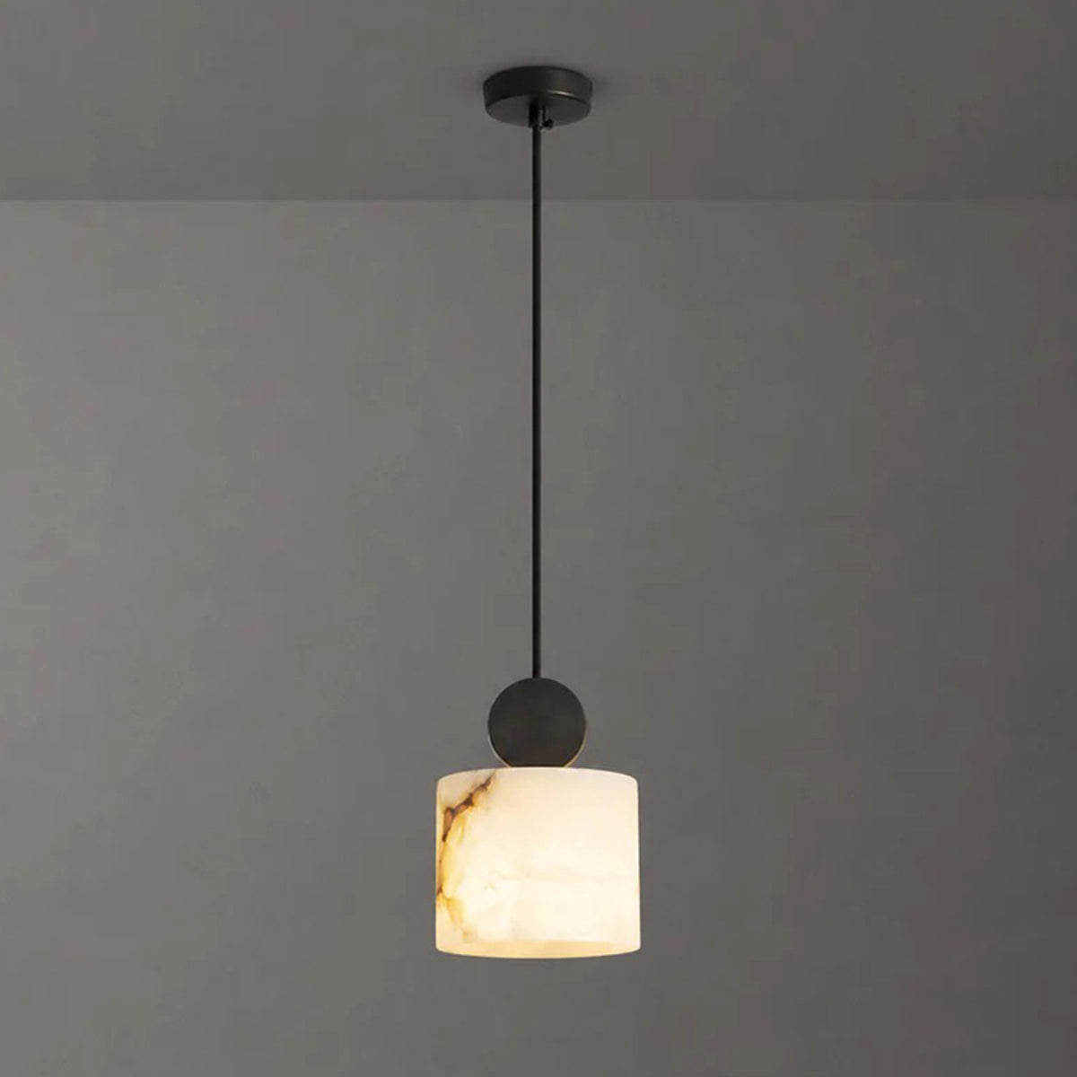 Sabine Alabaster Drum Pendant Light | Natural Alabaster and Brass | Symmetrical view of the drum stone fixture fully illuminated against a charcoal grey background | Severn Lighting