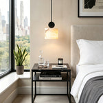Sabine Alabaster Drum Pendant Light | Natural Alabaster and Brass | Focused view of a single pendant illuminating a sleek bedroom nightstand against a skyline window | Severn Lighting