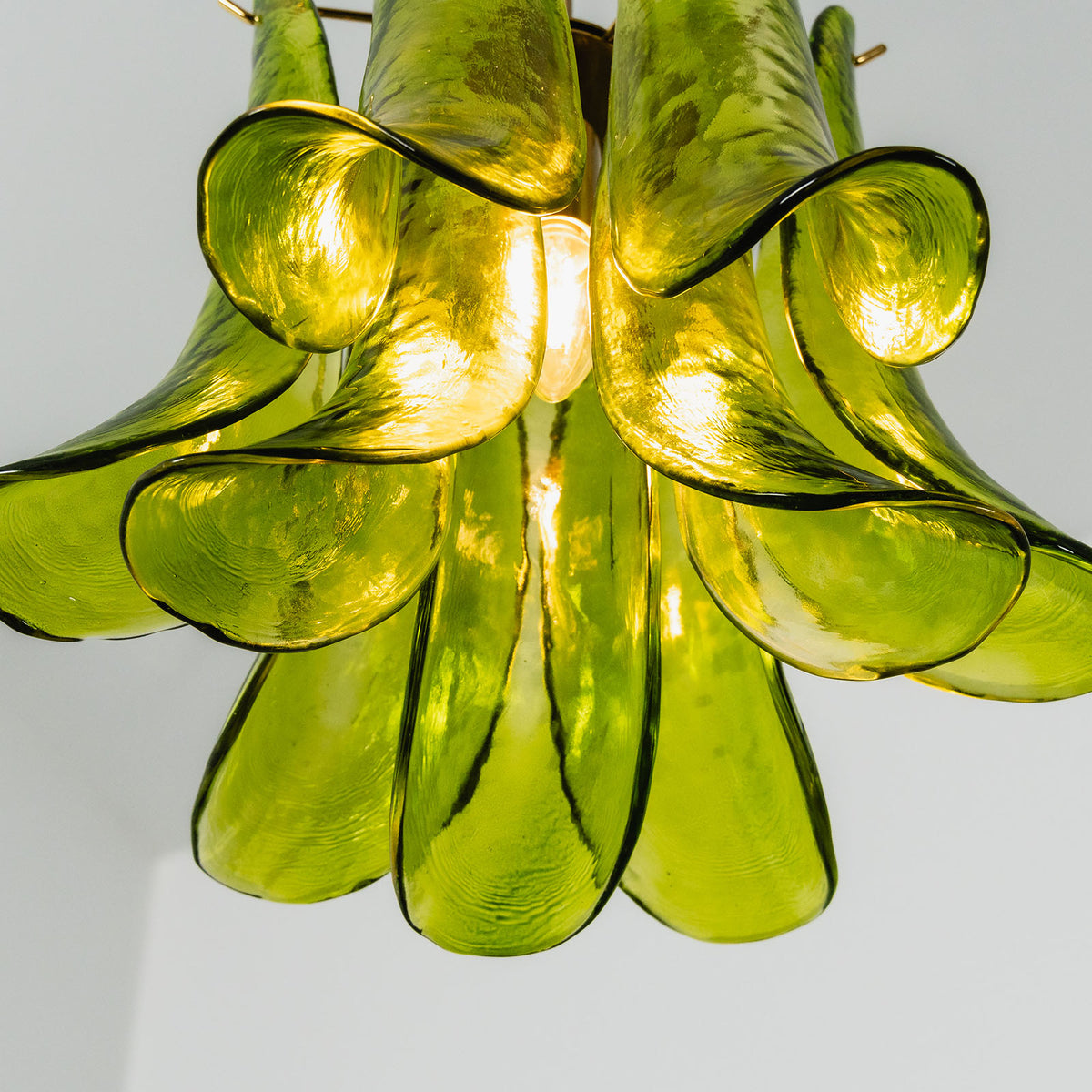 Semoy Curved Glass Petal Pendant Light | Curved Glass and Brass | Bottom perspective view of the glowing green glass petal shade emitting warm light | Severn Lighting