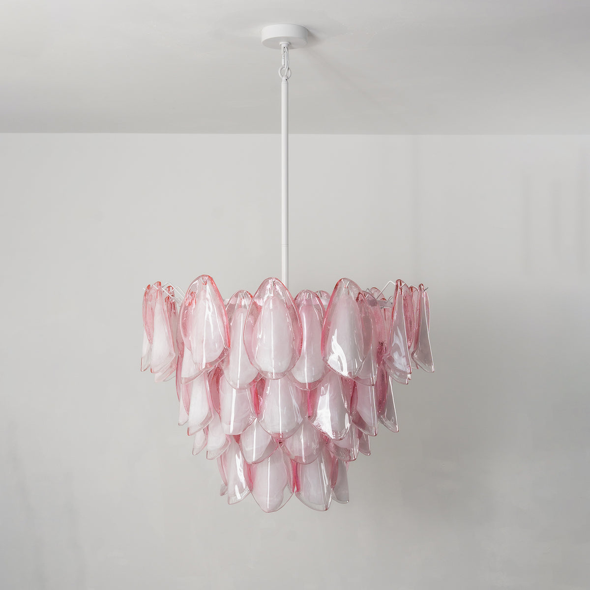 Seraphina Rose Glass Petal Chandelier | Glass, Metal | Staged unlit view of the pink glass fixture hanging elegantly in a clean minimalist living space above a white fireplace mantle | Severn Lighting